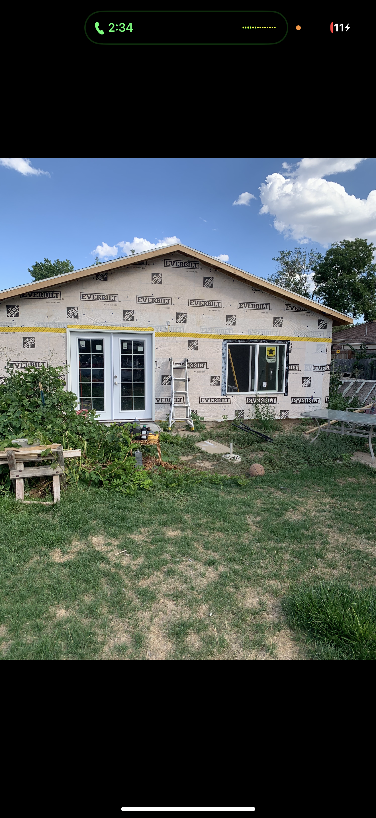 Construction progress with house wrap, windows, and French doors installed.