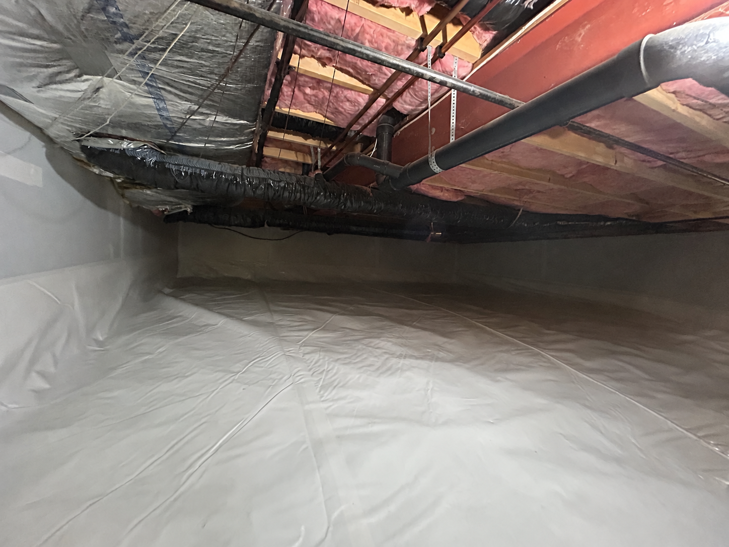 After encapsulation: crawl space floor and walls covered with a sealed white vapor barrier