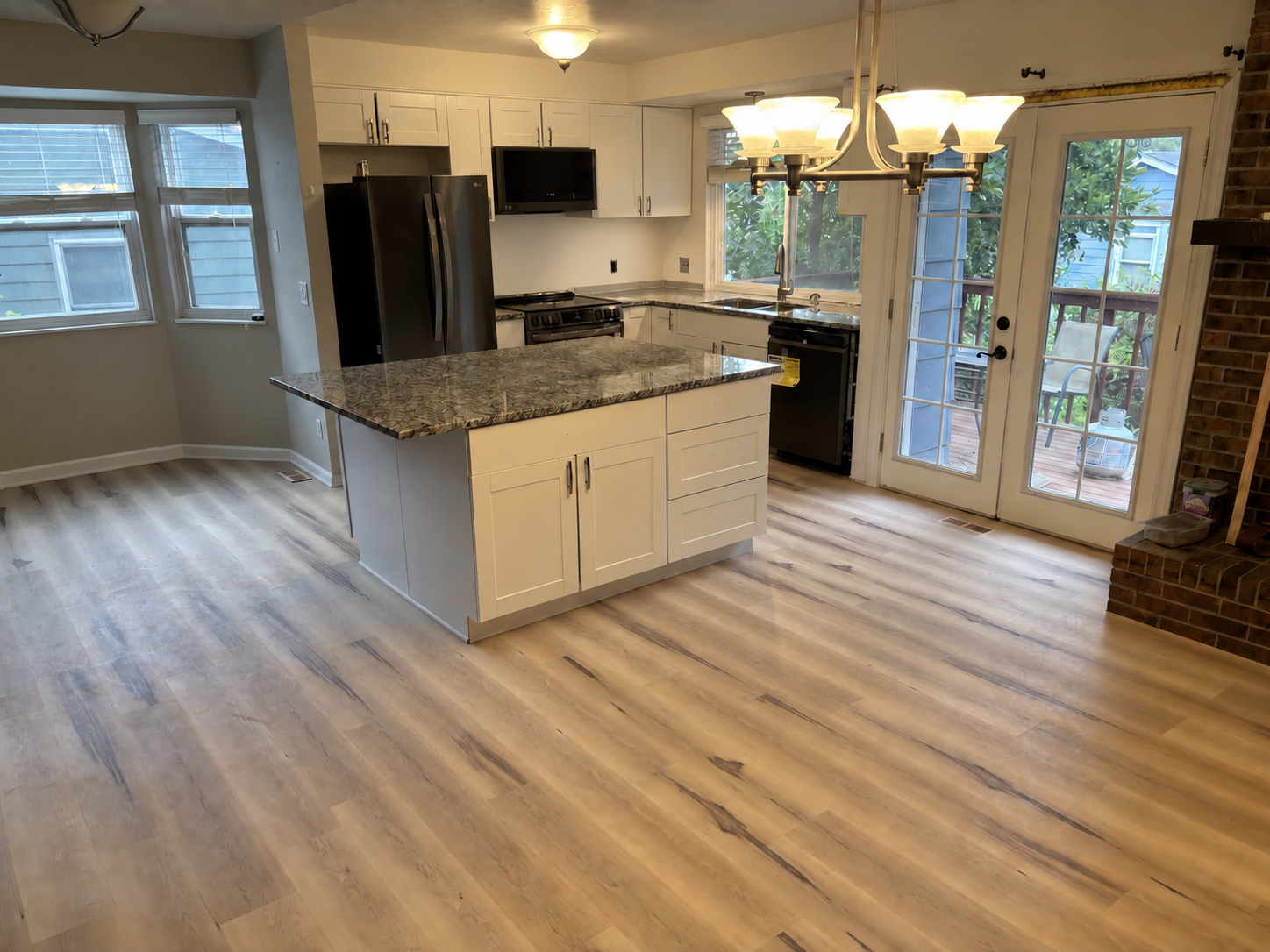 Kitchen with white cabinets, granite island, and wood-look flooring
